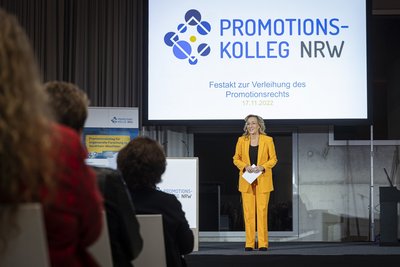 Die Moderatorin begrüßt die Anwesenden