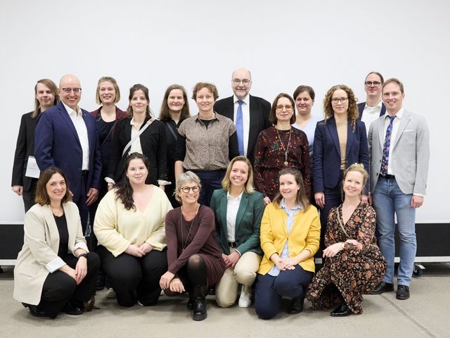 Gruppenfoto der Mitarbeitenden des PK NRW, die gemeinsam in die Kamera lächeln und mit dem Bild ihre Weihnachts- und Neujahrsgrüße übermitteln.